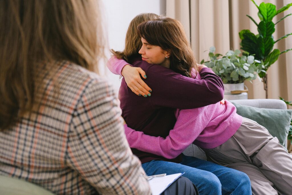 Side view of couple sitting on sofa and embracing during session with psychologist in light room in daytime